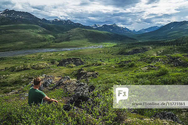 'Man sitting overlooking the Klondike Valley along the Dempster Highway; Yukon  Canada'