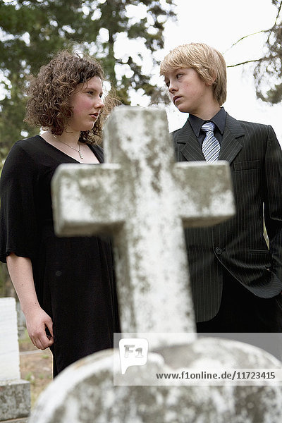 Ein Bruder und eine Schwester trösten sich gegenseitig an einem Grab auf einem Friedhof; Edmonton  Alberta  Kanada'.