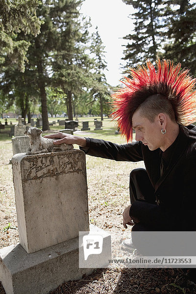 Ein junger Mann besucht einen Grabstein auf einem Friedhof; Edmonton  Alberta  Kanada .
