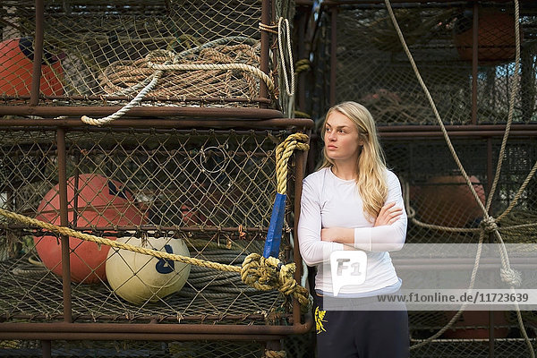Porträt einer jungen Frau vor kommerziellen Krabbenfischtöpfen im Hafen von King Cove  Alaska-Halbinsel; Südwest-Alaska  Vereinigte Staaten von Amerika'.
