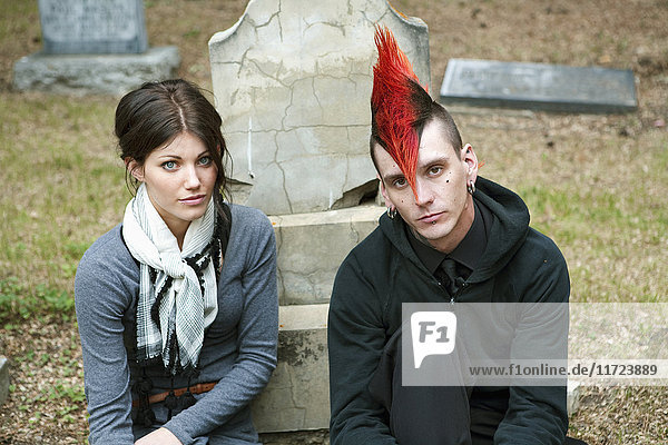 Ein junger Mann und eine junge Frau sitzen an einem Grabstein auf einem Friedhof; Edmonton  Alberta  Kanada .