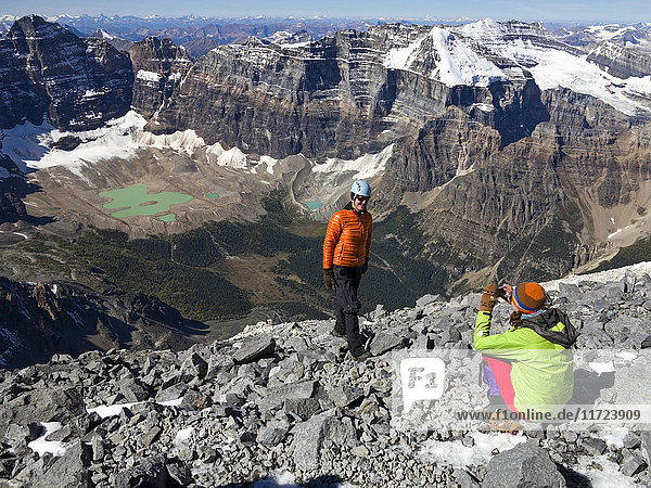Ein Vater posiert  während seine Tochter bei einer Wanderung in den Rocky Mountains ein Foto macht; Banff  Alberta  Kanada'.