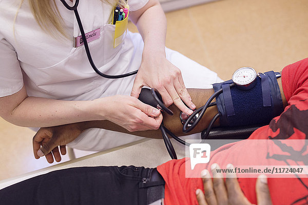 Doctor measuring young man's blood pressure