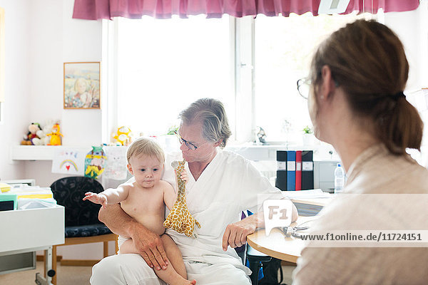 Baby (12-17 Monate) mit Mutter und Arzt im Untersuchungsraum