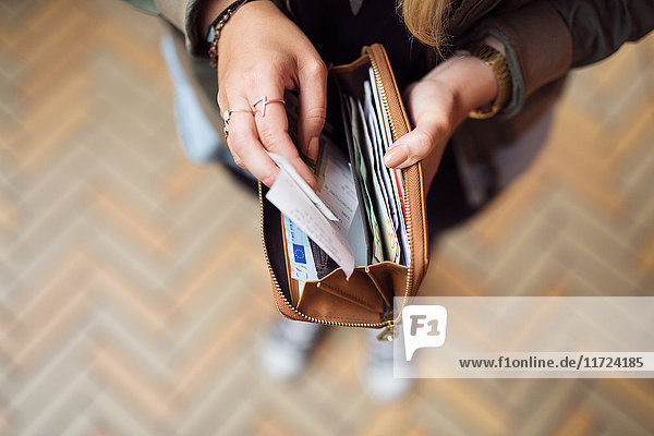 Frau hält offene Brieftasche mit Geldscheinen und Quittungen