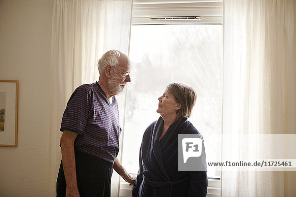 Senior couple standing next to window