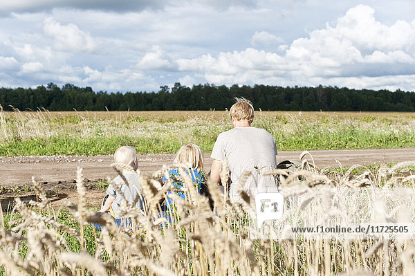 Father with children sitting near field
