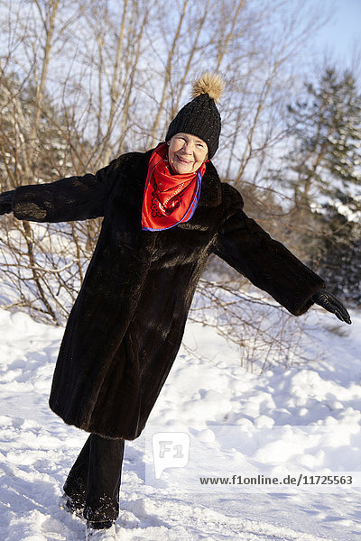 Senior woman walking in forest in winter