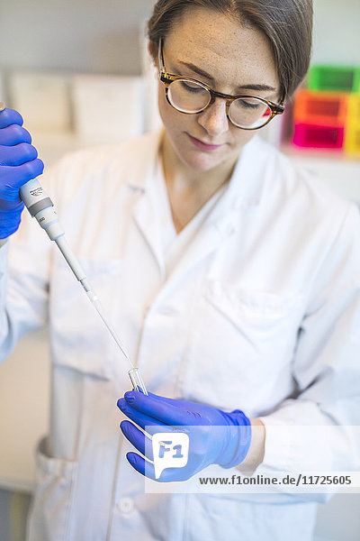 Technician holding pipette during research in laboratory