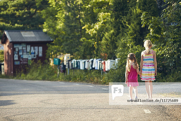 Girls holding hands while walking on road