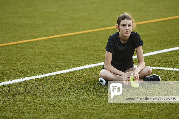 Teenager-Mädchen sitzt auf einem Spielfeld