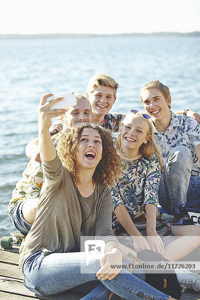 Glückliche Freunde machen ein Selfie am Wasser