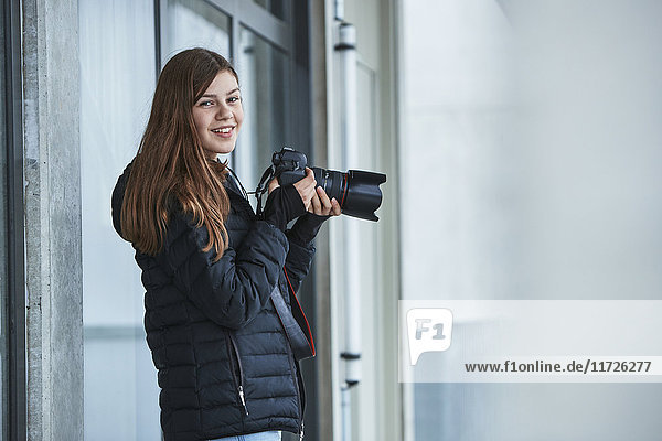Lächelndes jugendliches Mädchen mit Digitalkamera