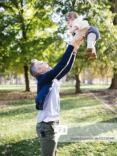 Vater wirft Tochter (12-17 Monate) im Park in die Luft