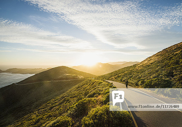 USA  Kalifornien  San Francisco  Kalifornien  Mann geht auf Küstenstraße bei Sonnenuntergang