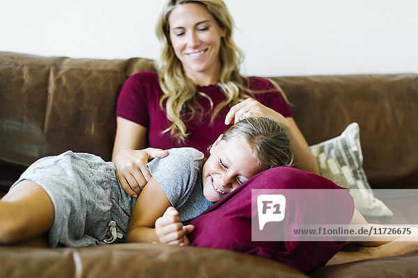Frau sitzt mit Tochter (6-7) auf Couch