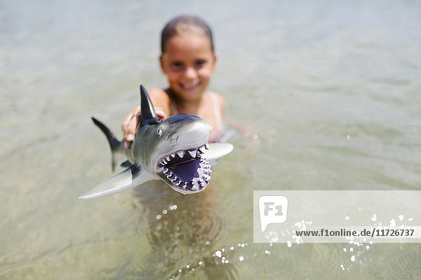 Mädchen (6-7) spielt mit Spielzeug-Hai im Meer