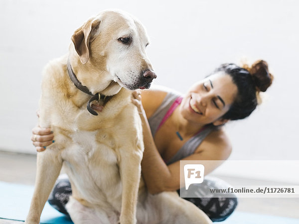 Frau übt Yoga mit Hund