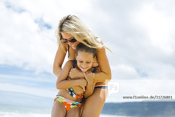 Mutter und Tochter (6-7) umarmen sich am Strand