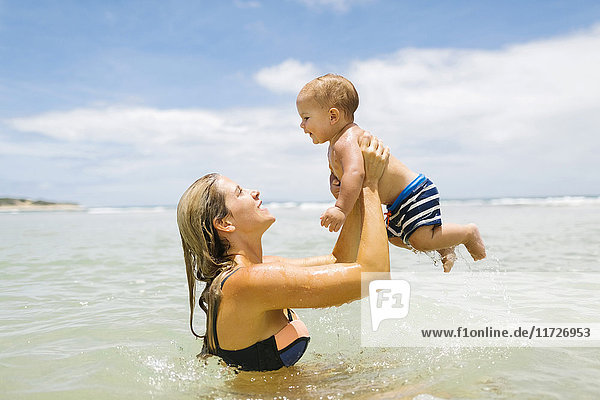 Mother playing with son (12-17 months) in sea