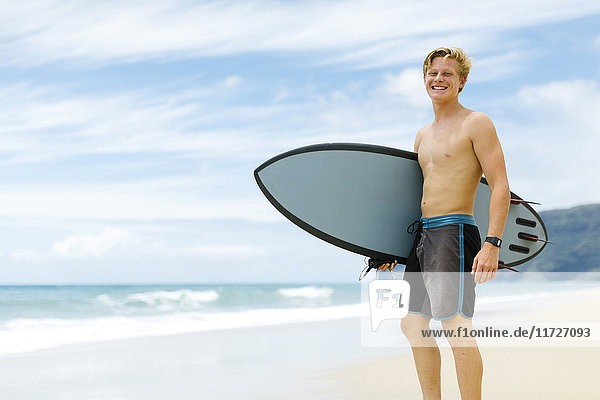 Man standing on beach and holding surfboard