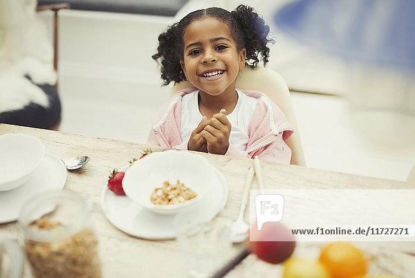 Portrait smiling girl eating breakfast at table