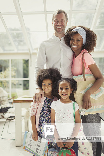Portrait smiling multi-ethnic young family ready to leave the house