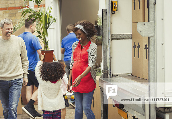 Multi-ethnic young family unloading moving van outside new house