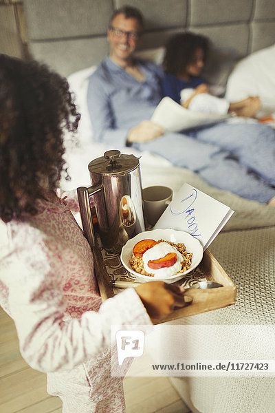Girl serving breakfast in bed and card to father on Father’s Day