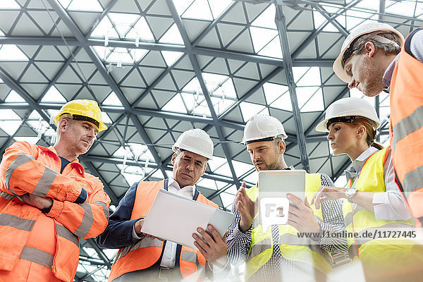 Vorarbeiter und Bauarbeiter mit digitalen Tabletts bei der Baustellenbesprechung