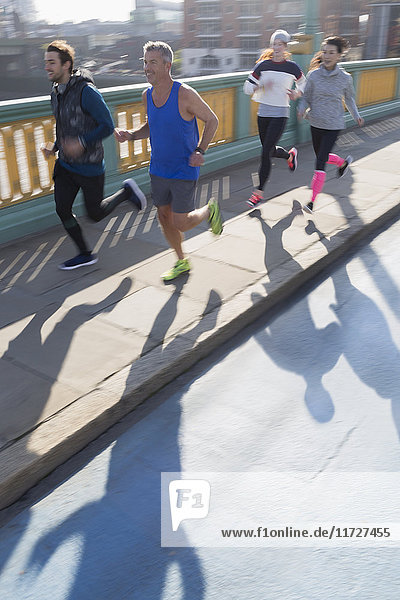 Läufer  die auf dem sonnigen Bürgersteig der Stadtbrücke laufen.