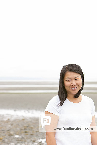 Portrait lächelnde Chinesin am bedeckten Strand