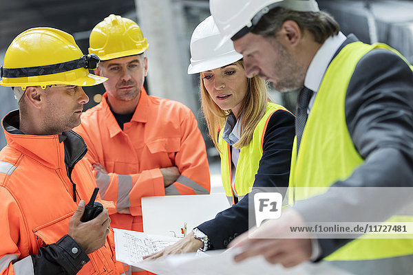 Ingenieure und Bauarbeiter bei der Überprüfung von Bauplänen auf der Baustelle