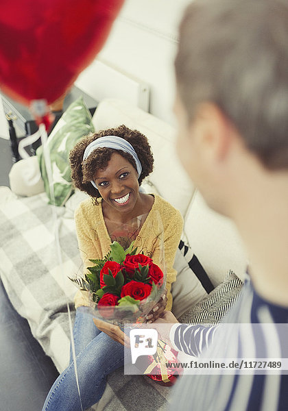 Husband giving Valentine’s Day rose bouquet and balloon to wife