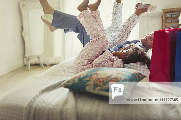 Vater und Töchter im Pyjama treten die Beine auf das Bett.