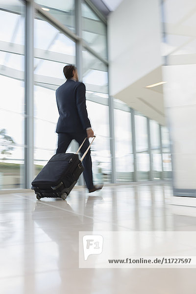 Businessman walking  pulling suitcase in airport