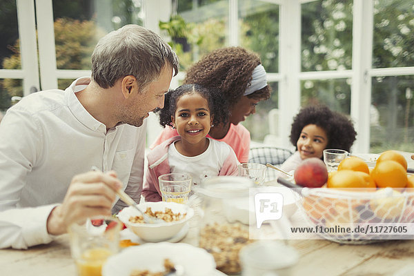 Portrait smiling multi-ethnic young family eating breakfast at table