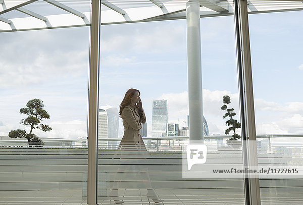 Businesswoman talking on cell phone on urban balcony with city view