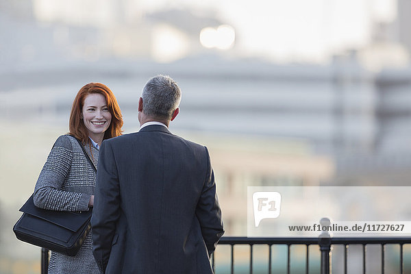 Businessman and businesswoman talking at urban railing