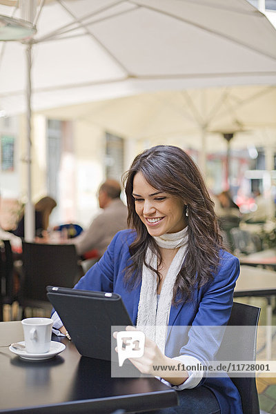 Porträt einer Frau mit Tablette bei einem Kaffee im Freien