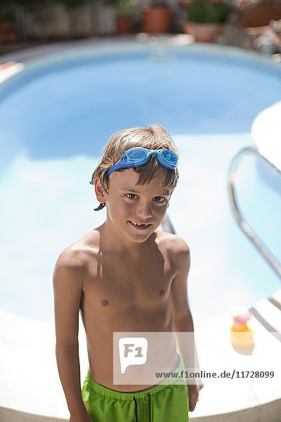Porträt eines süßen blonden Jungen mit Schwimmbrille im Pool