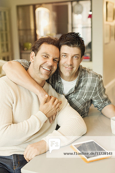 Portrait smiling  affectionate male gay couple with digital tablet hugging