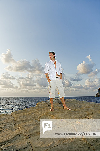 Porträt eines Mannes  der in einer Klippe am Meer steht.