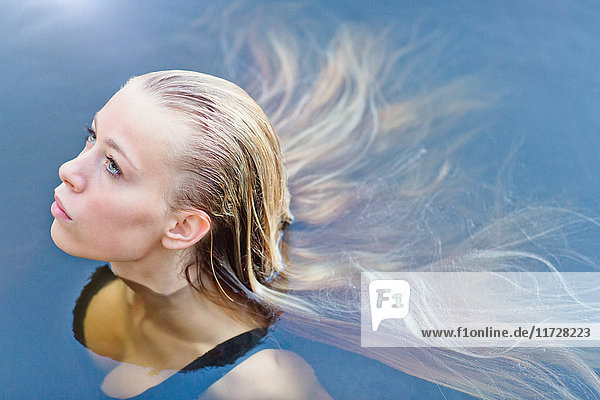 Porträt schönes blondes Teenager-Mädchen mit langen Haaren schwimmt im Schwimmbad