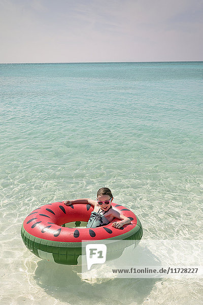 Portrait Mädchen schwimmt in Wassermelone aufblasbaren Ring in sonnigen tropischen blauen Ozean