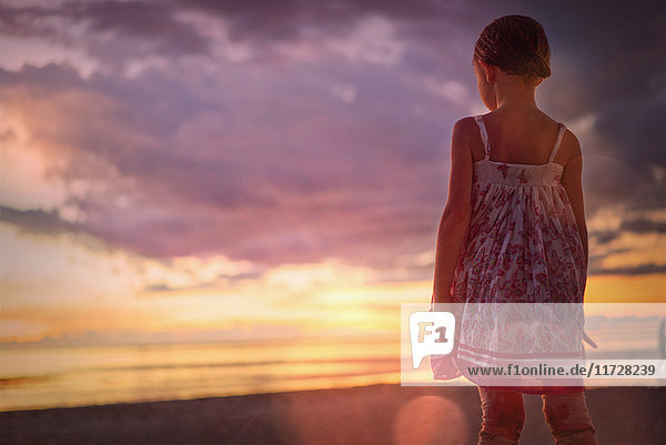 Nachdenklich Mädchen beobachten ruhigen Sonnenuntergang in dramatischen Himmel über dem Meer