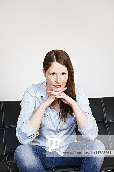 Porträt einer Frau mit Blick auf die Kamera auf dem Sofa