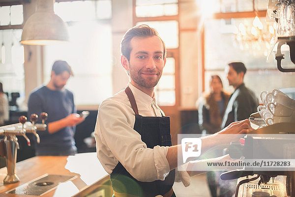 Portrait smiling male barista using espresso machine in cafe