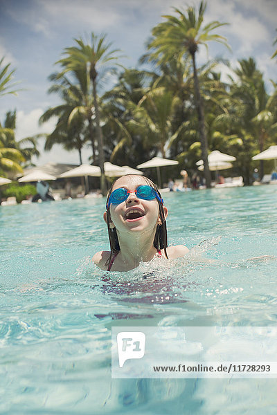 Porträt verspieltes Mädchen schwimmen mit Schwimmbrille in sonnigen tropischen Ozean