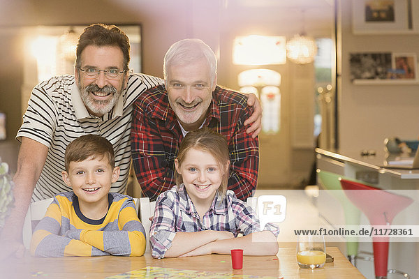 Portrait lächelnde männliche schwule Eltern und Kinder beim Brettspiel am Tisch